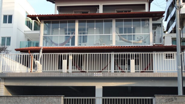 Un edificio de varios pisos con balcón, escaleras y entrada protegida por un portón.