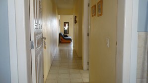 Un pasillo con una cama, una puerta y una pared con tres cuadros enmarcados.