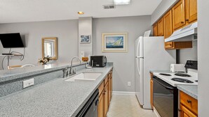 A kitchen with granite countertops, a double sink, wooden cabinets, a refrigerator, a stove, and a microwave.