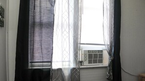 A room with a window, air conditioning unit, and a curtain. - Bella's Boutique Hotel (Hemingway)