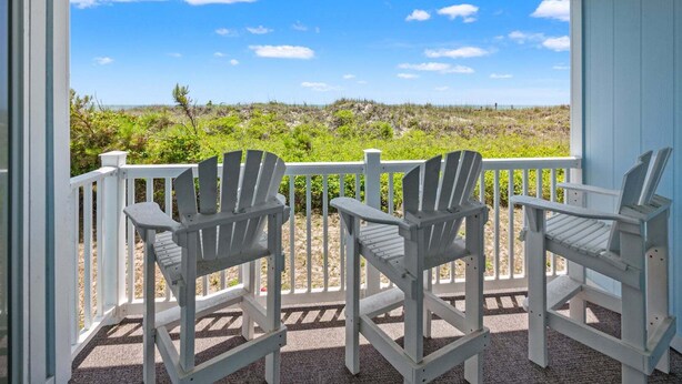 Une véranda avec deux fauteuils Adirondack donnant sur la plage.