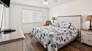 A bedroom with a bed, bedside tables, a lamp, a ceiling fan, and a window with blinds. - Soothing stay at this oceanfront condo w/pool, sundeck, priv balc, grill in popular North Myrtle (North Myrtle Beach)