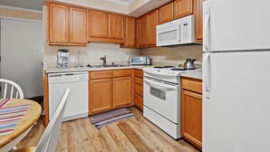 Una cocina con armarios de madera, un microondas, una estufa y un refrigerador.
