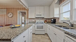 A kitchen with white cabinets, a granite countertop, a built-in oven, a microwave, a coffee maker, and a sink. - Oceanfront, dog-friendly vacation home w/gorgeous ocean views, large deck-steps from beach (North Myrtle Beach)