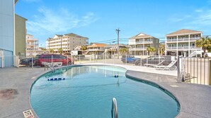 A swimming pool with a 3ft depth marker, surrounded by a fence, with buildings in the background.