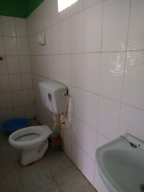 Ein kleines Badezimmer mit Toilette, einem blauen Waschbecken und einer Badewanne.