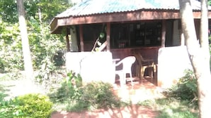Una estructura de madera rústica con techo de lámina corrugada, rodeada de follaje y árboles.