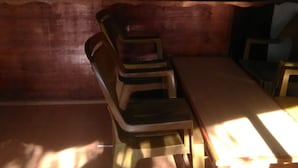 Zona de bar tenuemente iluminada, con mobiliario de madera y una barra mostrando diferentes botellas.