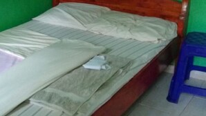 Una cama individual con cabecera de madera en una habitación con paredes verdes.