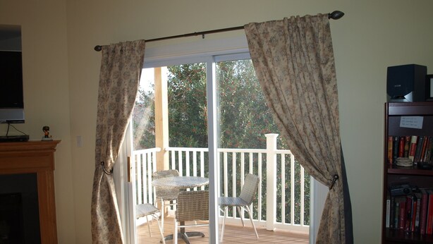 A room with a sliding glass door to an outdoor deck, a fireplace, and a bookshelf. - Rehoboth Beach Condo (Rehoboth Beach)