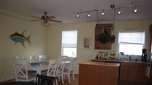 A kitchen with a dining area, wooden cabinets, a ceiling fan, and a fish decoration on the wall. - Rehoboth Beach Condo (Rehoboth Beach)