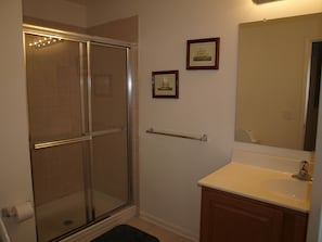 A bathroom with a glass shower enclosure, a sink with a mirror, and a towel rack. - Rehoboth Beach Condo (Rehoboth Beach)