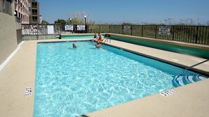 Una piscina rectangular con un indicador de profundidad de 0,9 metros, rodeada por una cerca con letreros de advertencia.