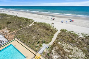 A beach with a pool and a path leading to the beach. - Updated & spacious oceanfront family condo rental w/amazing views, pool, hot tubs in North Myrtle! (North Myrtle Beach)