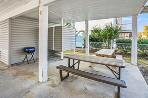 Zona de porxo coberta amb taula de pícnic i barbacoa.