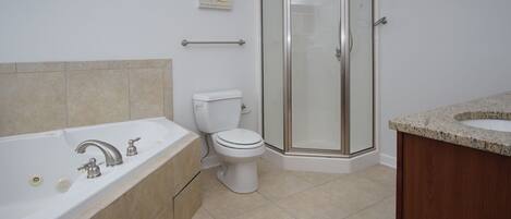 A bathroom with a bathtub, toilet, and glass-enclosed shower.