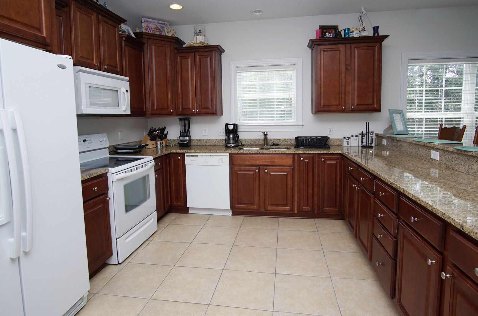 A kitchen with wooden cabinets, a white refrigerator, a microwave, a stove, and a dishwasher.