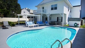 Une piscine avec une maison blanche en arrière-plan.