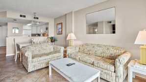 A living room with two patterned sofas, a coffee table, and a dining area with a kitchen in the background. - Oceanfront panoramic views, indoor pool, Jacuzzi, balcony--in favorite North Myrtle Beach (North Myrtle Beach)