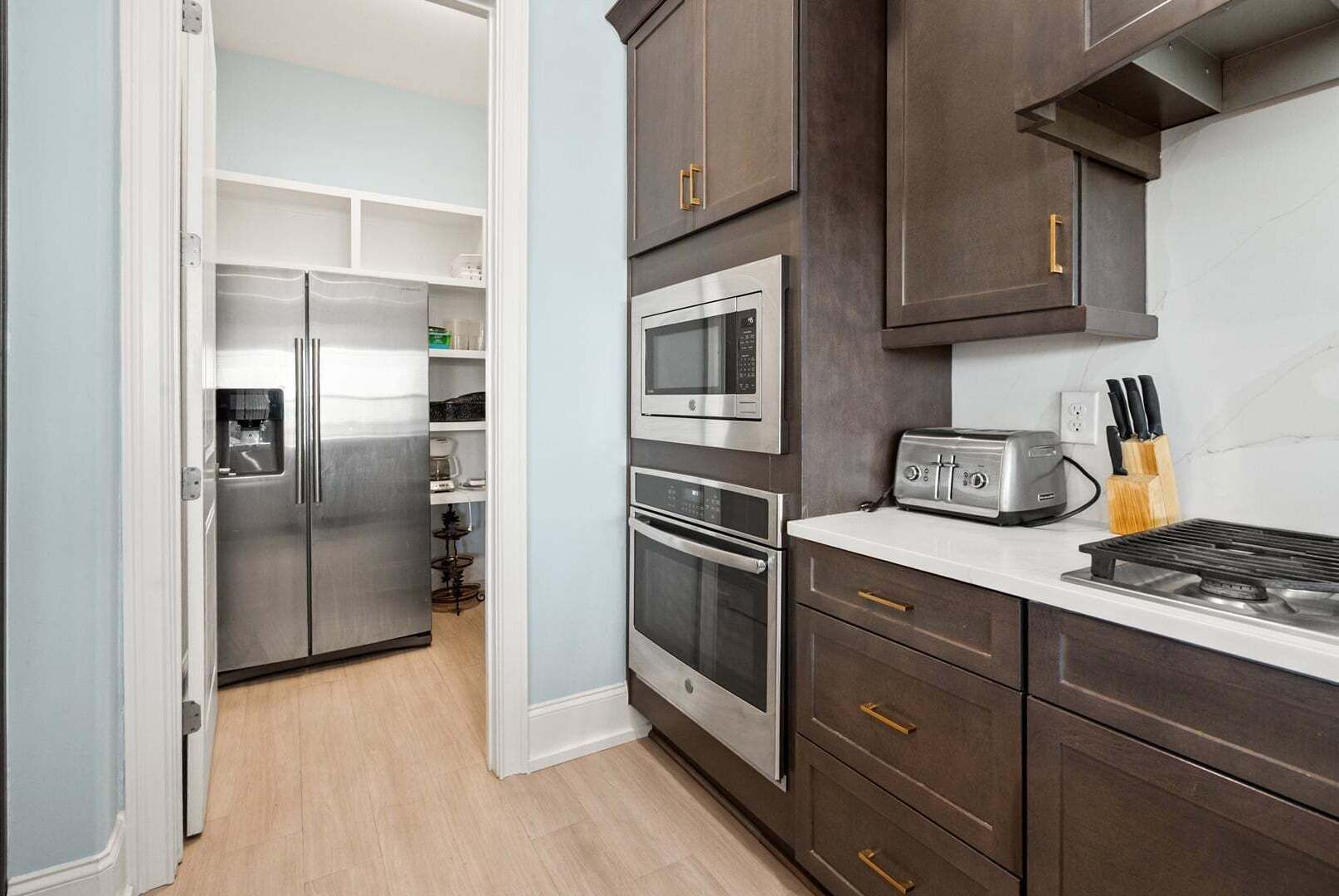 A kitchen with a refrigerator, microwave, toaster, and oven.