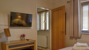 A hotel room with a bed, a desk with a chair, a television, a radiator, and a window with blinds. - 4 bedroom accommodation in Lower Cwm-twrch, near Ystradgynlais (Lower Cwm-twrch, near Ystradgynlais)
