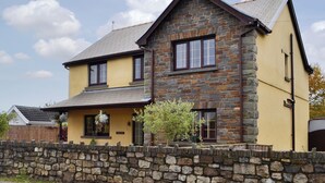 A two-story house with a stone facade, a yellow exterior, and a stone wall in front. - 4 bedroom accommodation in Lower Cwm-twrch, near Ystradgynlais (Lower Cwm-twrch, near Ystradgynlais)