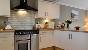 A kitchen with a stove, oven, and white cabinets. - 4 bedroom accommodation in Lower Cwm-twrch, near Ystradgynlais (Lower Cwm-twrch, near Ystradgynlais)