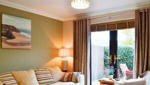 A cozy living room with a sofa, a small table, and a chair. There is a lamp on the table, and a painting on the wall. - 4 bedroom accommodation in Lower Cwm-twrch, near Ystradgynlais (Lower Cwm-twrch, near Ystradgynlais)