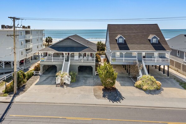 A beachfront motel with two-story buildings, a covered walkway, and a view of the ocean.