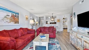 Ein Wohnzimmer mit roten Sofas, einem Couchtisch und einem Fernseher auf einer Holzkommode.