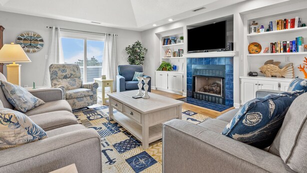 A living room with a fireplace, sofas, a coffee table, and a bookshelf. - Gorgeous blvd home, pet-friendly w/private pool, and beautiful decks in North Myrtle (North Myrtle Beach)