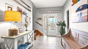 A hallway with a wooden bench, a console table with a lamp, and a wall with a nautical-themed sign. - Gorgeous blvd home, pet-friendly w/private pool, and beautiful decks in North Myrtle (North Myrtle Beach)