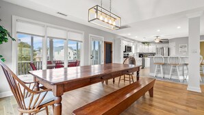 A modern kitchen with white cabinets, a wooden dining table, and a bench. - Gorgeous blvd home, pet-friendly w/private pool, and beautiful decks in North Myrtle (North Myrtle Beach)
