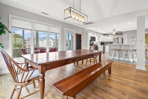 Enjoy meals in the kitchen with a dining table and bench, offering a view of the outside through large windows.