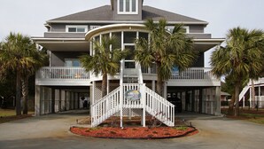 A two-story building with a balcony, palm trees, and a white staircase leading to the entrance. - Gorgeous blvd home, pet-friendly w/private pool, and beautiful decks in North Myrtle (North Myrtle Beach)