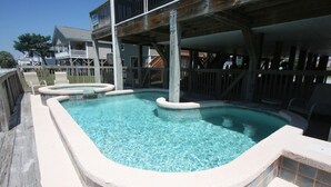Une piscine dotée d’une terrasse en bois et d’un espace abrité.