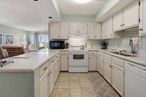 A kitchen with white cabinets, a microwave, stove, and a dishwasher.