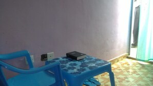 Ein Zimmer mit einem blauen Plastiktisch und -stuhl, einer gemusterten Tischdecke und einem Buch auf dem Tisch.