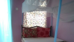 Ein Einzelbett mit Baldachin, eine Wand mit Muster und ein gefliester Boden.