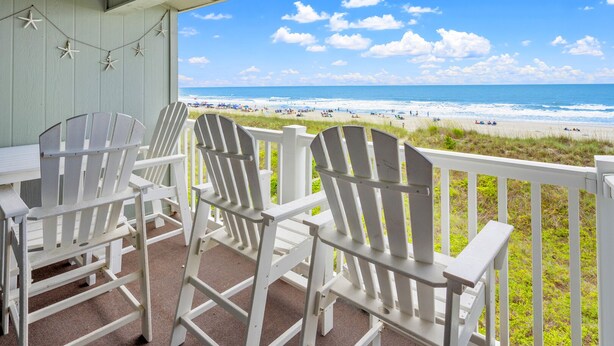 A covered outdoor seating area with white Adirondack chairs and a view of the beach. - Beautiful, dog-friendly w/amazing ocean views (North Myrtle Beach)