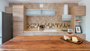 A modern kitchen with wooden cabinets, a large island, and a tiled backsplash. - Alpujarra Arena (Soportujar)