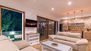 A modern living room with a sofa, a coffee table, and a TV mounted on the wall. - Alpujarra Arena (Soportujar)