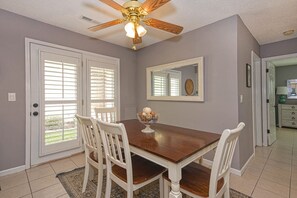 Enjoy meals in this dining area with a table and chairs, a ceiling fan, and a mirror on the wall.
