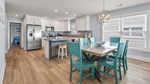A modern kitchen with white cabinets, a stainless steel refrigerator, and a granite countertop.