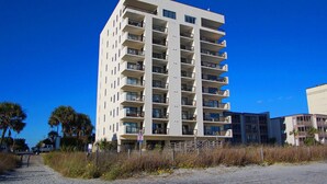 A multi-story hotel with balconies, located near a beach with palm trees. - Beautiful ocean & beach views, oceanfront condo w/pool, sundeck, family friendly-North Myrtle Beach (North Myrtle Beach)
