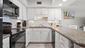 A modern kitchen with white cabinets, granite countertops, stainless steel appliances, and a tiled backsplash. - Beautiful ocean & beach views, oceanfront condo w/pool, sundeck, family friendly-North Myrtle Beach (North Myrtle Beach)