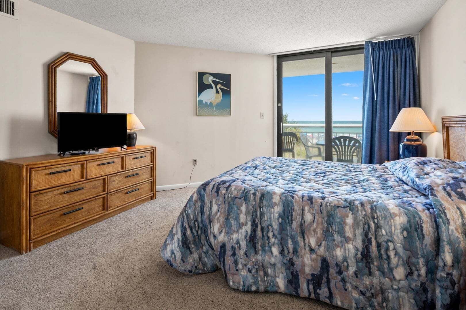 Une chambre à coucher avec un lit, une commode, un téléviseur et un tableau.