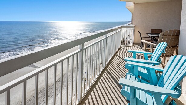 A balcony with a view of the ocean, featuring a table and chairs. - Enjoy direct access to your private oceanfront balcony (North Myrtle Beach)
