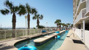 A pool area with multiple lanes, lounge chairs, and palm trees. - Enjoy direct access to your private oceanfront balcony (North Myrtle Beach)