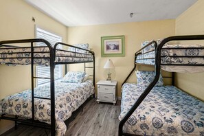 A room with bunk beds, a bedside table with a lamp, and a framed picture on the wall. - Oceanfront duplex steps from beach w/shared pool, game room, kids' pool, grill (North Myrtle Beach)